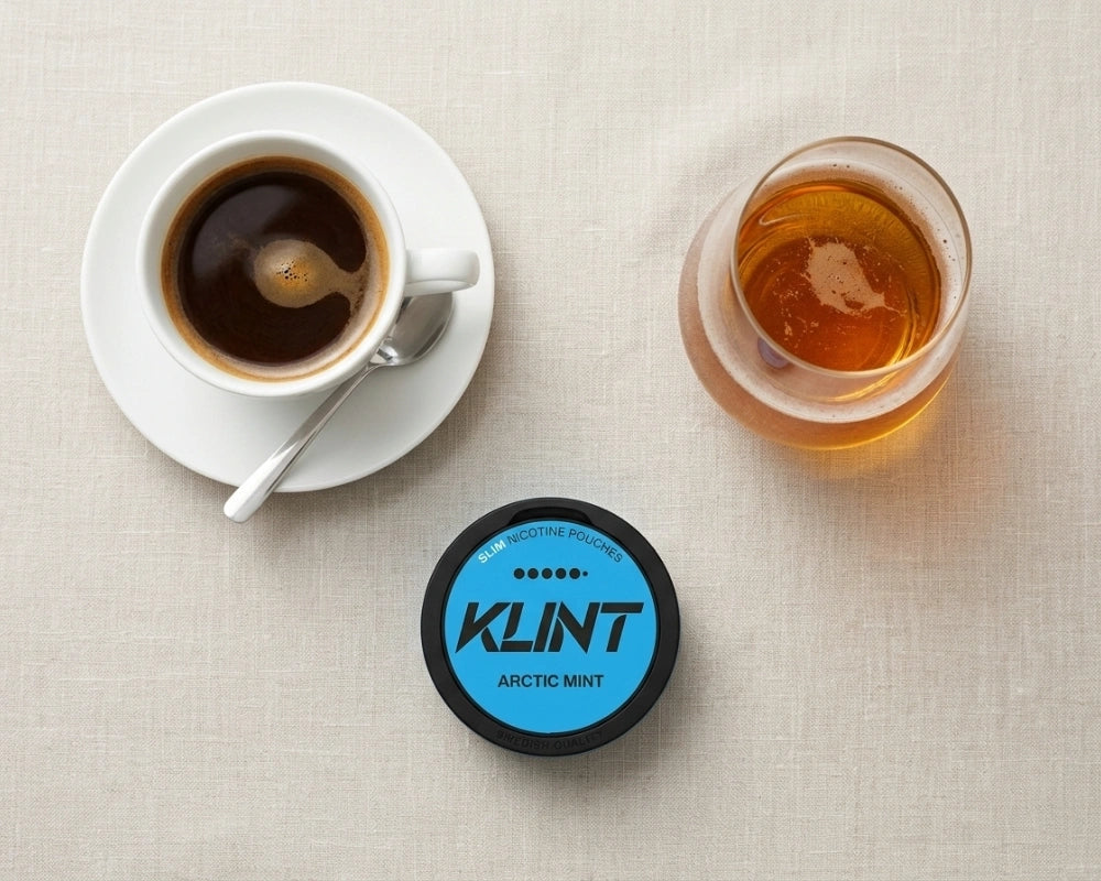 Filiżanka espresso, szklanka whisky i saszetka nikotynowa KLINT Arctic Mist widziane z góry
